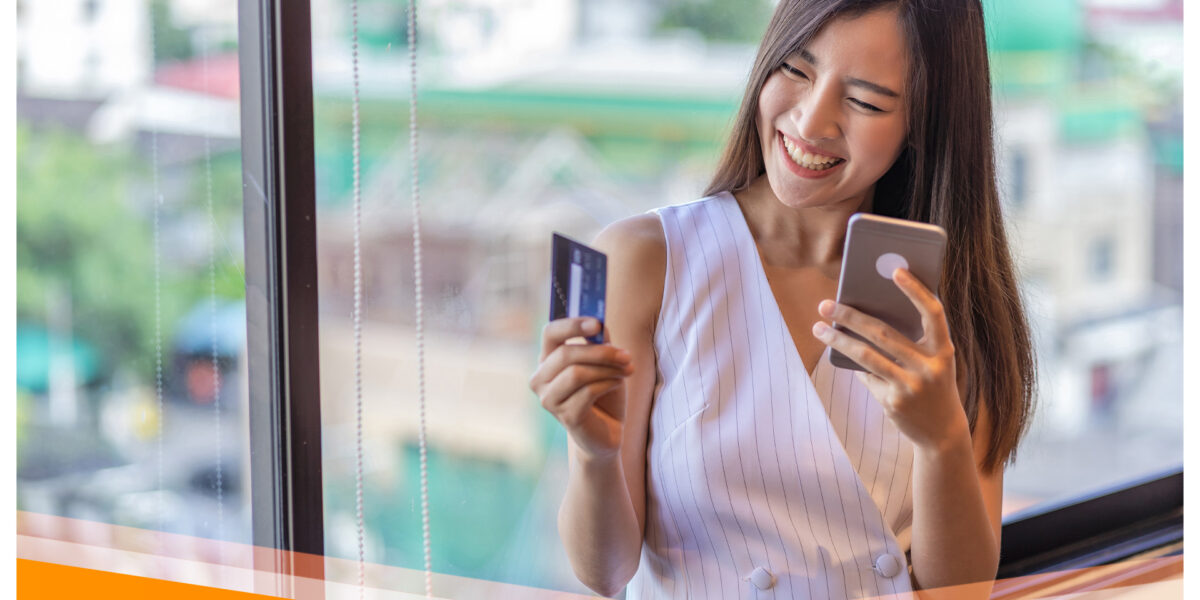Zdjęcie kobiety trzymającej telefon komórkowy oraz kartę płatniczą