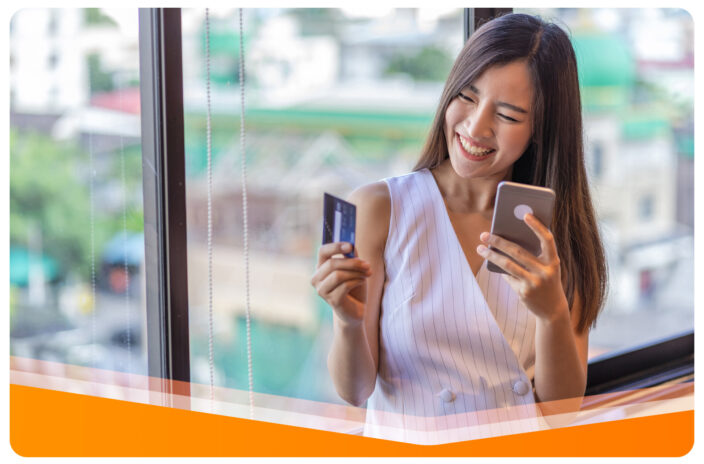 Zdjęcie kobiety trzymającej telefon komórkowy oraz kartę płatniczą